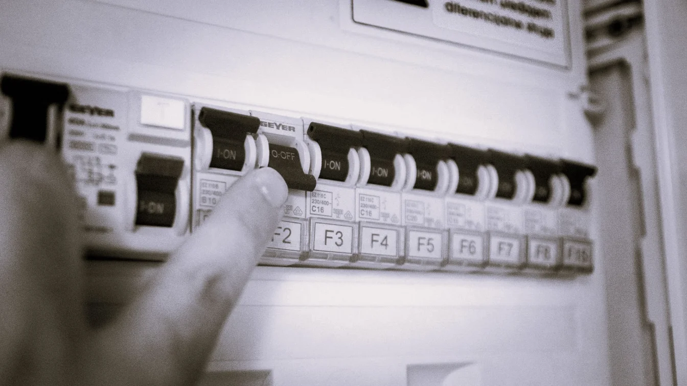 Ruka koja dodiruje osigurače u razvodnoj kutiji – vizuelna provera oštećenja izolacije žica u elektroinstalacijama
