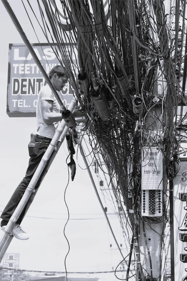 Električar pored neuredne instalacije sa zapetljanim kablovima na banderi – primer preopterećenja i lošeg održavanja elektroinstalacija
